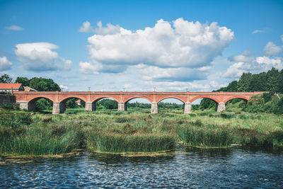 Arch bridge over river against sky