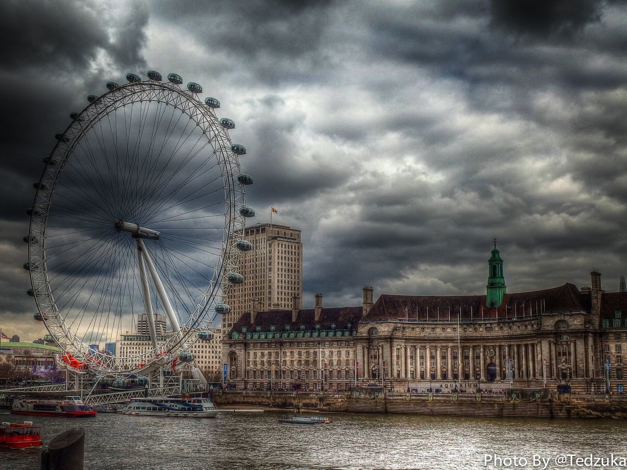 sky, architecture, cloud - sky, cloudy, built structure, building exterior, water, city, weather, ferris wheel, overcast, river, travel destinations, waterfront, capital cities, storm cloud, tall - high, cloud, amusement park ride, famous place