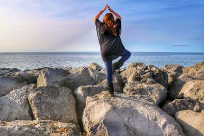 Rear view of woman on rock at sea shore