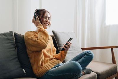 Side view of woman sitting on sofa at home
