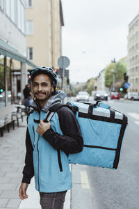 Portrait of smiling delivery man on sidewalk in city