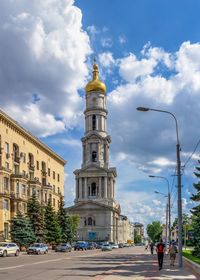 View of street and buildings against cloudy sky