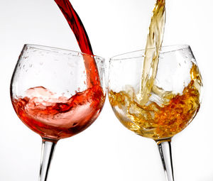 Close-up of wineglass on glass against white background