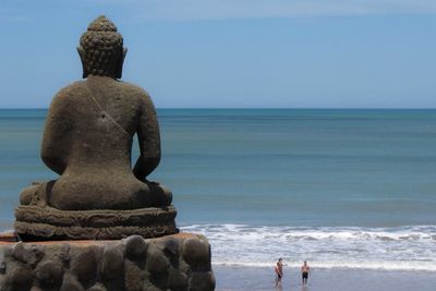 Buddha sculpture in front of sea against sky
