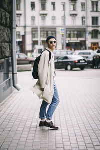 Portrait of teenage boy standing on footpath in city