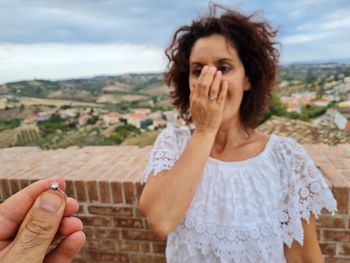 Male hand holds out the ring as a marriage proposal and the girl is amazed and happy