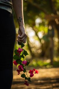 Midsection of woman holding flowers while standing outdoors