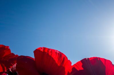 Low angle view of red flags against clear blue sky