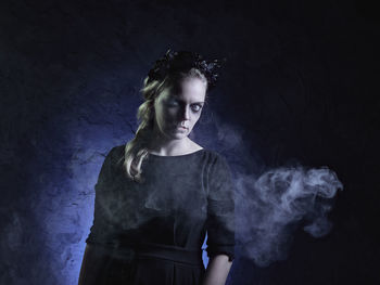 Portrait of spooky woman standing against black background