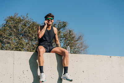 Portrait of man wearing sunglasses against blue sky