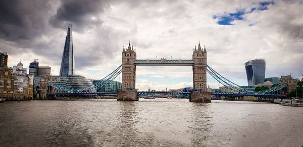 View of tower bridge over the thames river against cloudy london sky