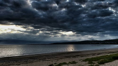 Scenic view of beach against cloudy sky