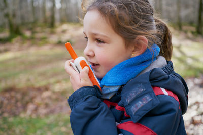 Cute girl talking on the radio while walking in the woods on winter