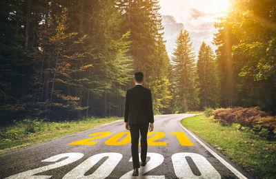 Rear view of man standing on road in forest