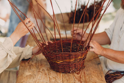 Midsection of people making wicker basket