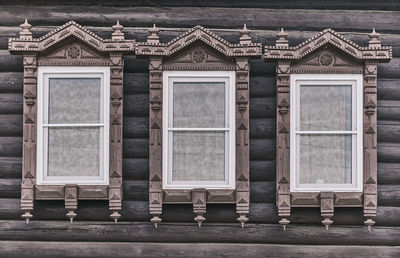 Wndows with carved wooden architraves. log facade of typical rural russian house.