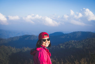 Smiling woman standing against mountains