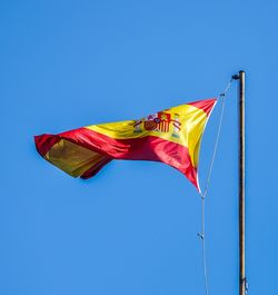 Low angle view of flag against clear blue sky