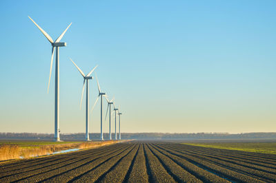 Wind turbines on field against sky