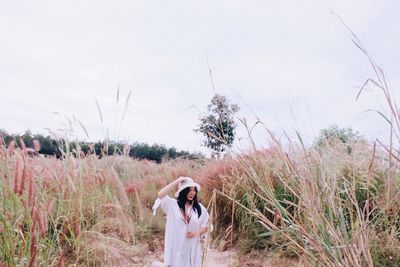 Woman standing on field against sky