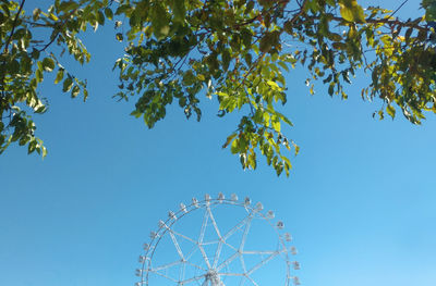 Low angle view of ferris wheel against clear blue sky