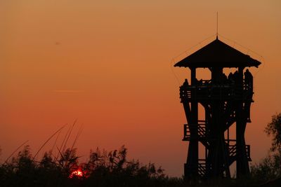 Silhouette lookout tower against orange sky during sunset