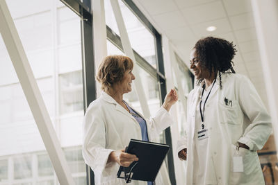 Female physician gesturing while talking with coworker at hospital