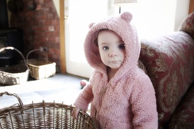 Portrait of cute baby girl in warm clothing standing at home
