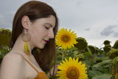 Portrait of young woman with sunflower against plants