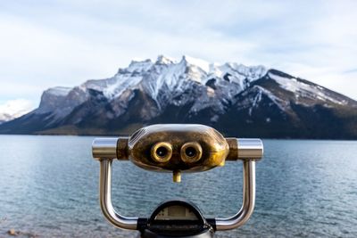 Close-up of coin-operated binoculars by lake against mountain