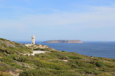 Lighthouse amidst sea and buildings against sky