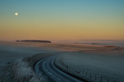 Scenic view of road against clear sky during sunrise