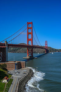 Suspension bridge over river against clear blue sky