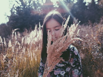 Girl with plants sitting on field