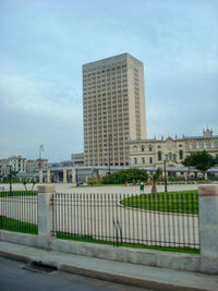 Road by buildings against sky in city