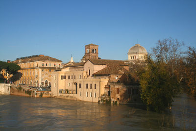 Buildings at waterfront against blue sky