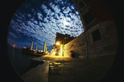 Illuminated building against cloudy sky