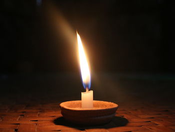 Close-up of lit candle in darkroom