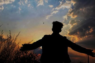 Rear view of silhouette man standing against sky during sunset