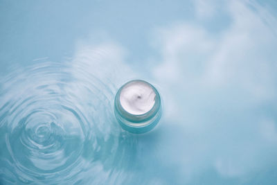 Cosmetic product on water with splashes. jar cream on aqua background, advertising natural cosmetics