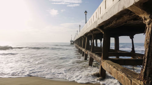 Wooden posts on beach against sky