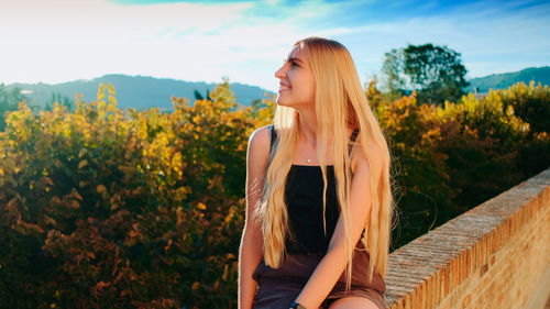 Beautiful young woman standing by plants