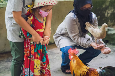 Young girl scared of the animal and being held by the brother.