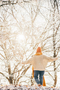 Rear view of woman standing against bare tree