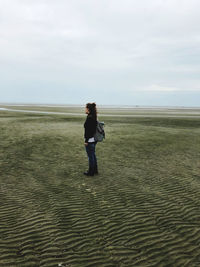 Full length of woman standing on beach against sky