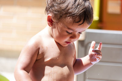 Happy little boy playing with water hose in the backyard