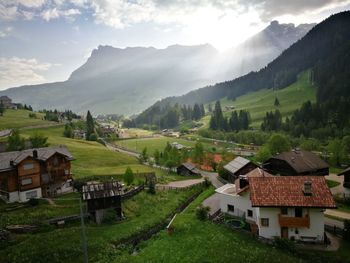 Houses on field by mountains against sky