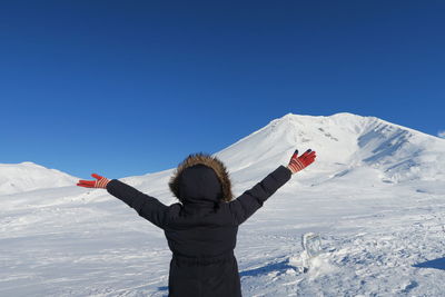 Rear view of person on snowcapped mountain against clear sky