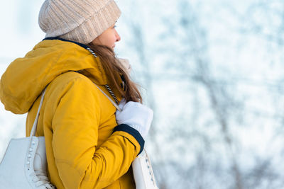 Portrait of young woman with ice skates against a backdrop of snow-covered trees