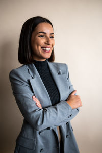 Portrait of young woman standing against gray background